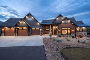 Front exterior of modern home with stone accents, large garage, and evening lighting