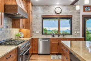 Kitchen with custom wood cabinetry, range hood, and warm pendant lighting
