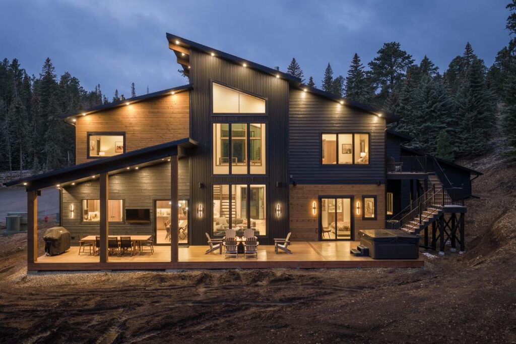 Rear view of modern mountain home with large windows and outdoor deck