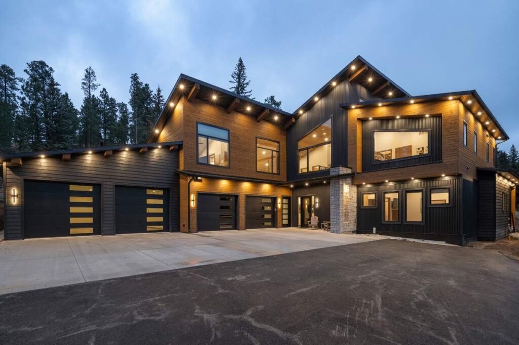 Luxury modern home exterior with wood siding and large garage at twilight