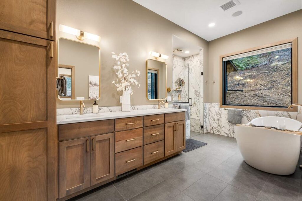 Modern bathroom with freestanding tub, marble walls, and wooden vanity