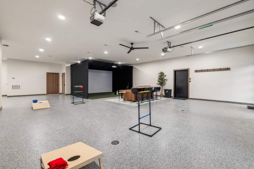 Spacious garage with polished concrete floor and indoor golf simulator setup